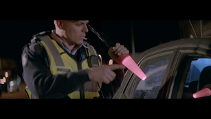 Police officer holding a glowstick approaching a vehicle